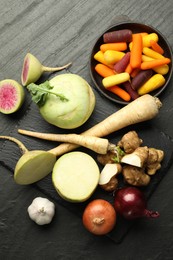 Photo of Different raw root vegetables on black table, flat lay