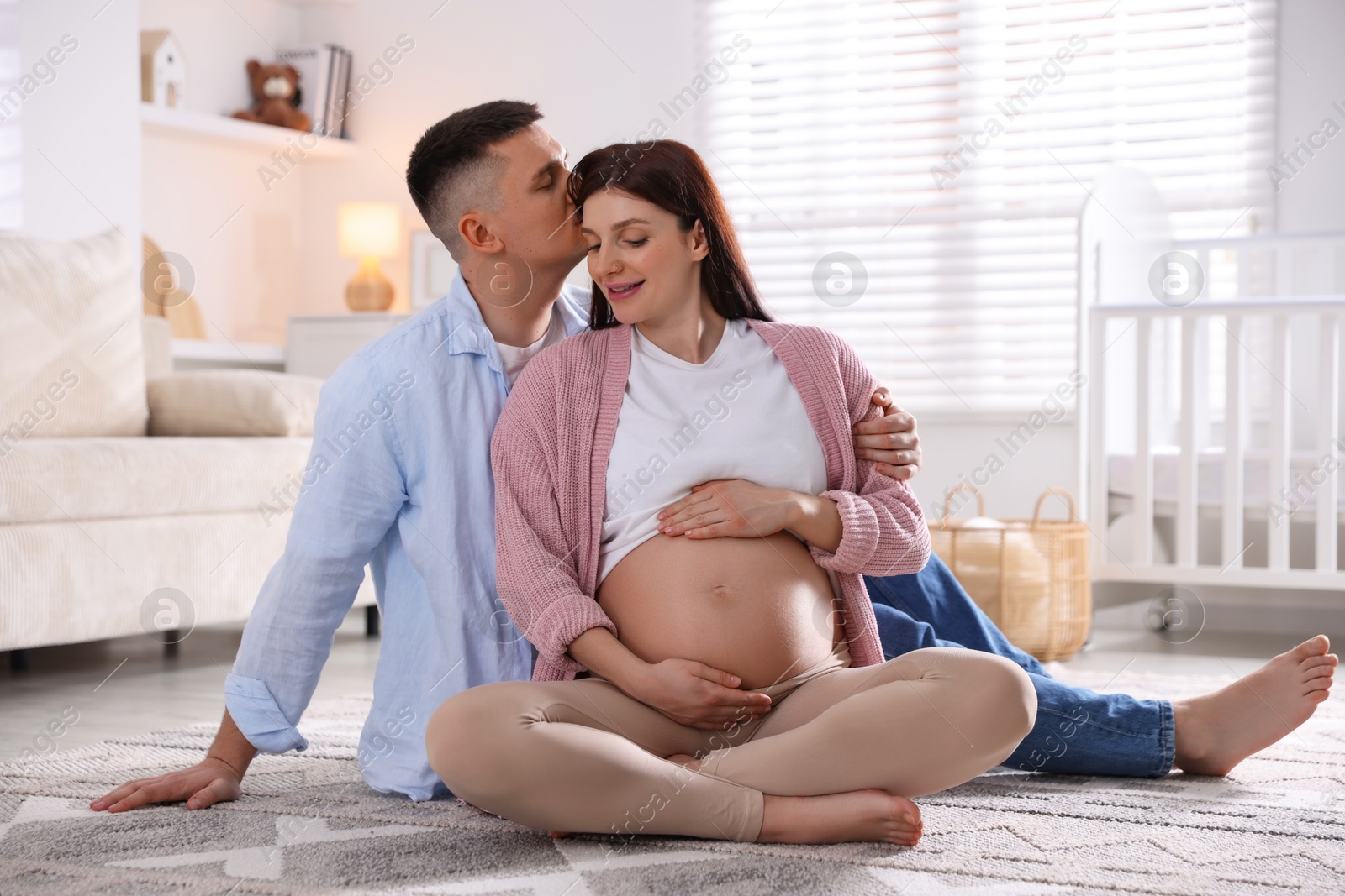 Photo of Pregnant woman and her husband on floor at home