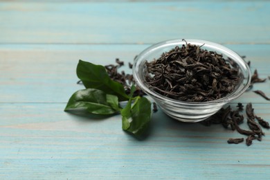 Photo of Dried and fresh tea leaves on blue wooden table, closeup