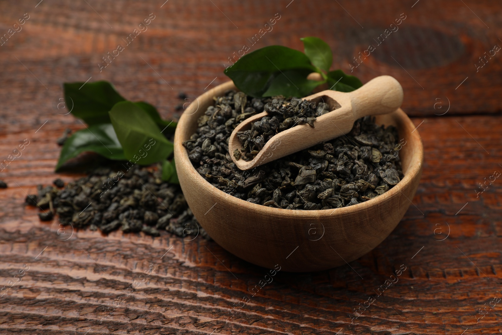 Photo of Dried and fresh tea leaves on wooden table, closeup