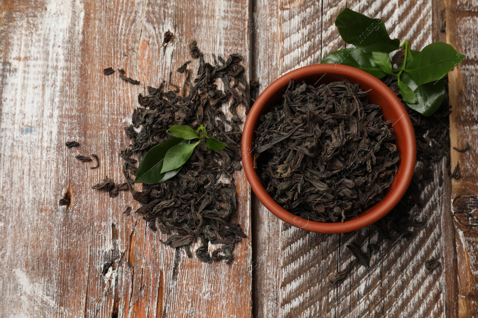 Photo of Dried and fresh tea leaves on wooden table, top view