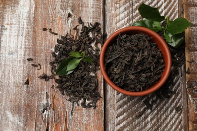 Photo of Dried and fresh tea leaves on wooden table, top view