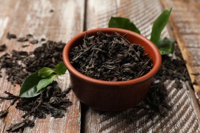 Photo of Dried and fresh tea leaves on wooden table, closeup