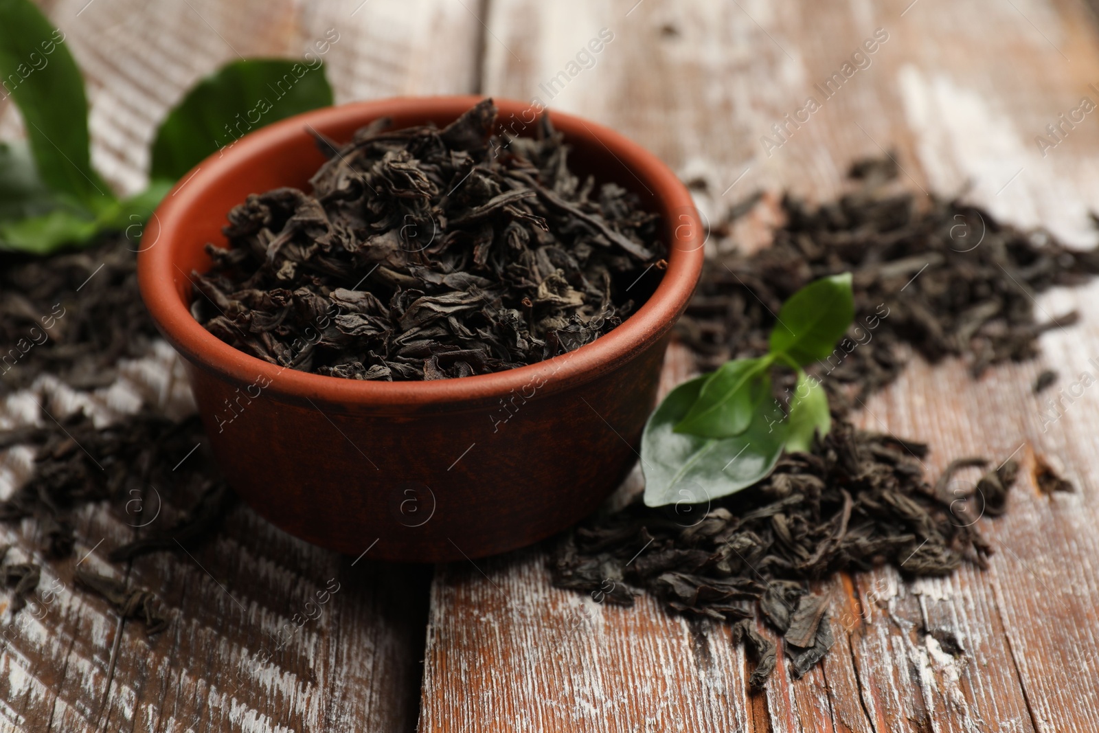 Photo of Dried and fresh tea leaves on wooden table, closeup