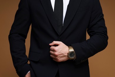 Photo of Man in classic suit with stylish watch on brown background, closeup