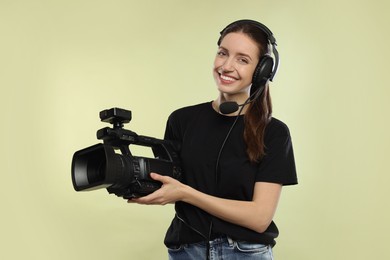 Photo of Happy woman with professional video camera on pale olive background