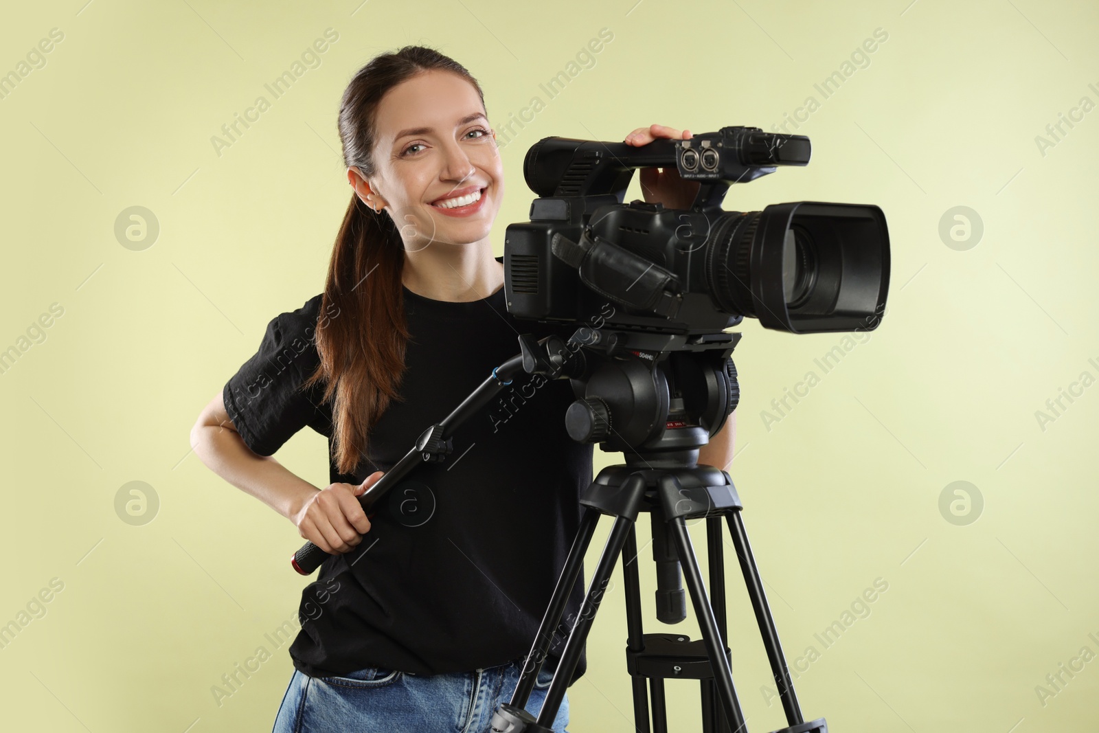 Photo of Happy woman with professional video camera on pale olive background