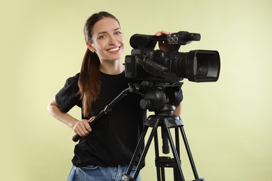 Photo of Happy woman with professional video camera on pale olive background