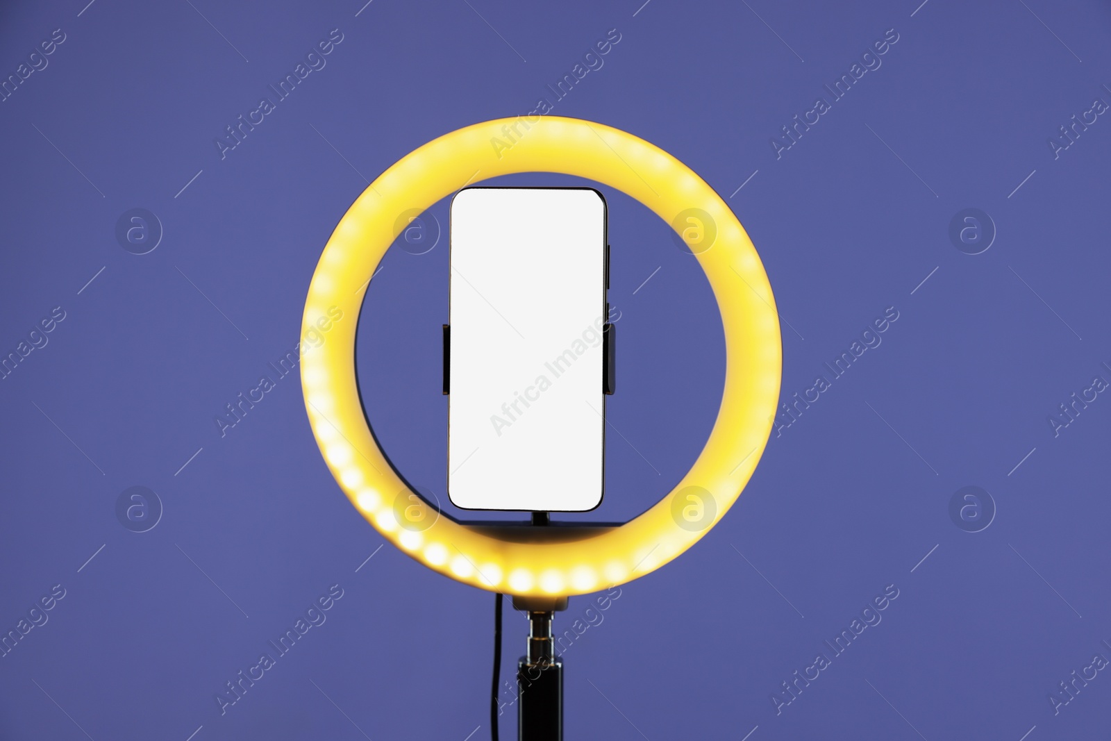 Photo of Ring lamp with smartphone on purple background