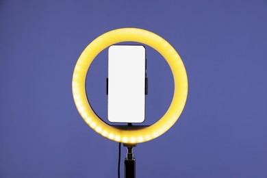 Photo of Ring lamp with smartphone on purple background