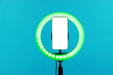 Photo of Ring lamp with smartphone on light blue background