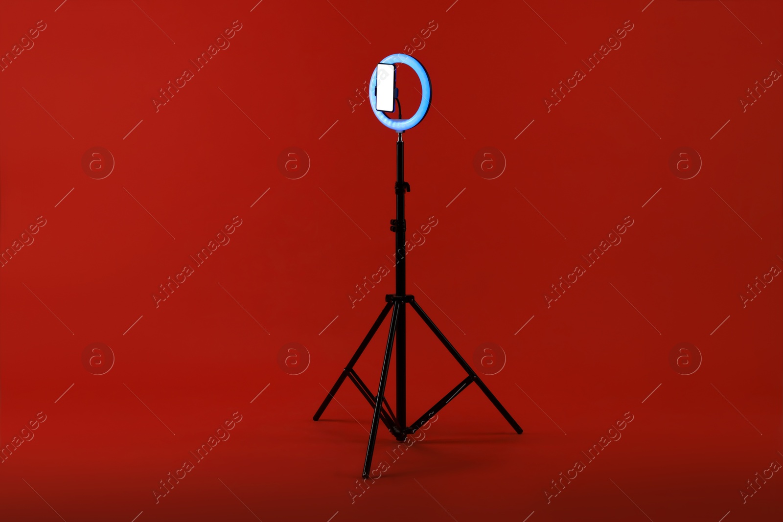 Photo of Ring lamp with smartphone on red background