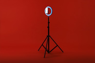 Photo of Ring lamp with smartphone on red background