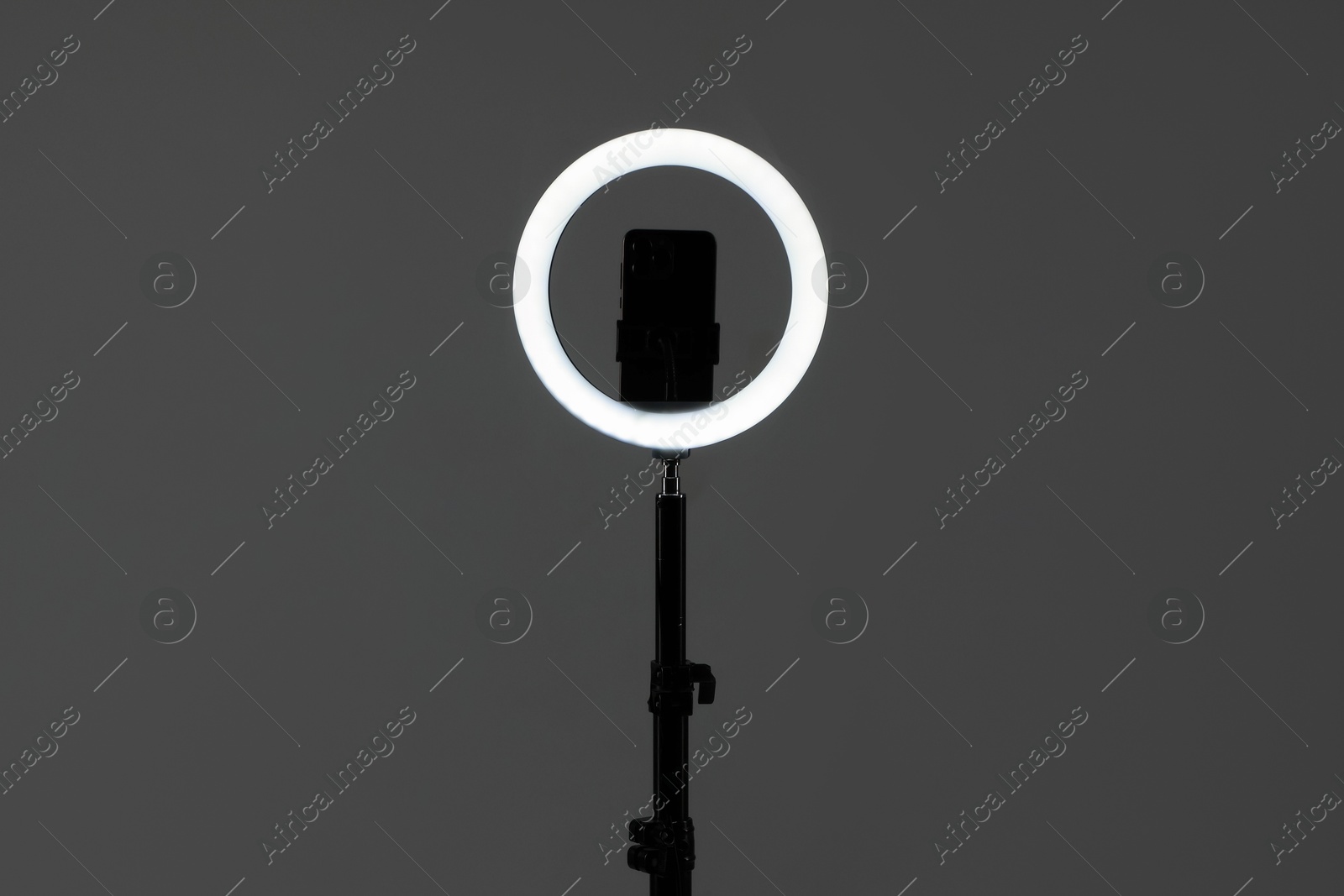 Photo of Ring lamp with smartphone on grey background