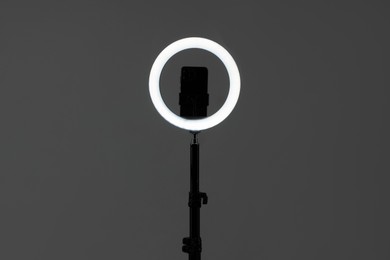 Photo of Ring lamp with smartphone on grey background