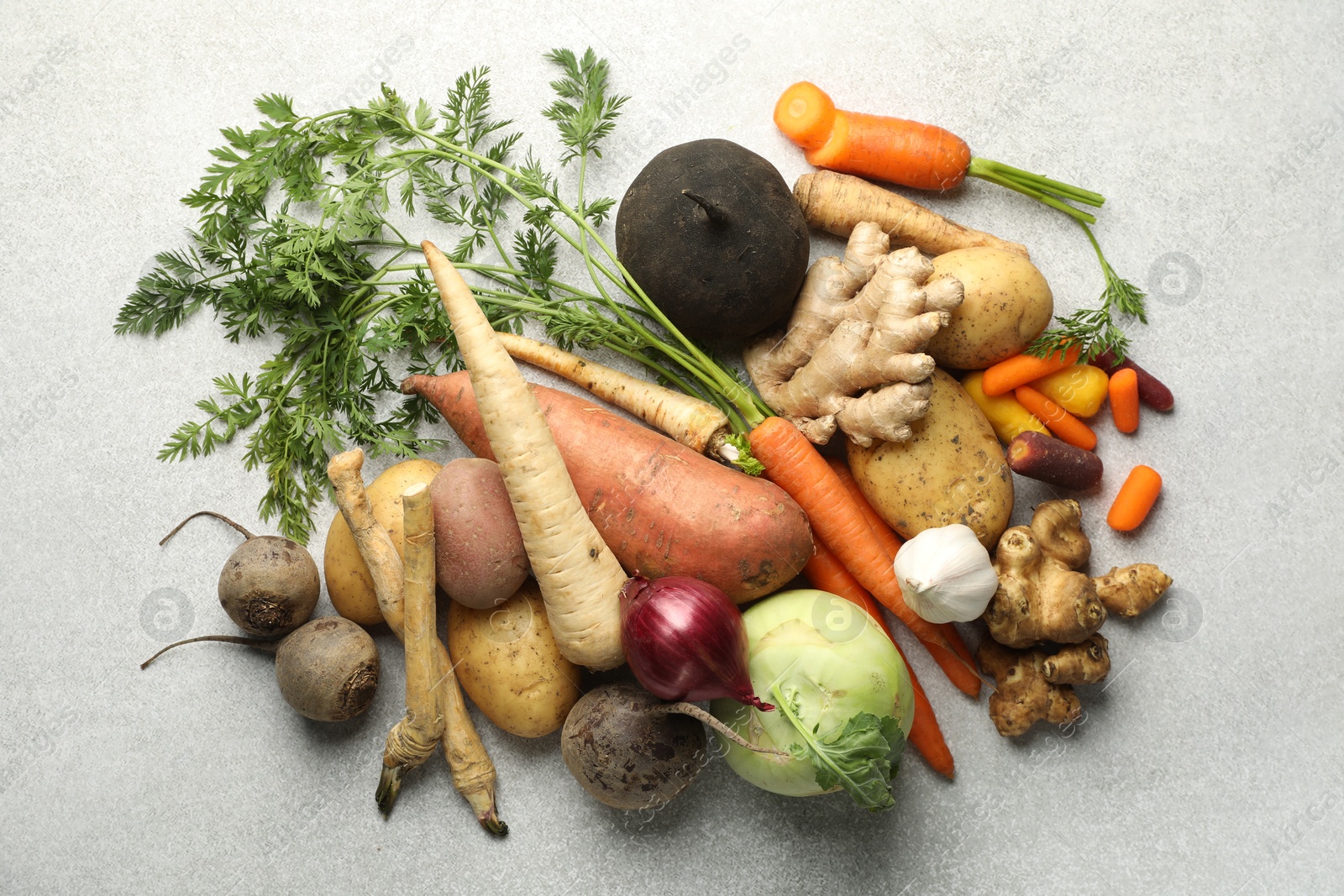 Photo of Different root vegetables on light grey table, flat lay