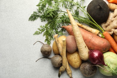 Photo of Different root vegetables on light grey table, flat lay. Space for text