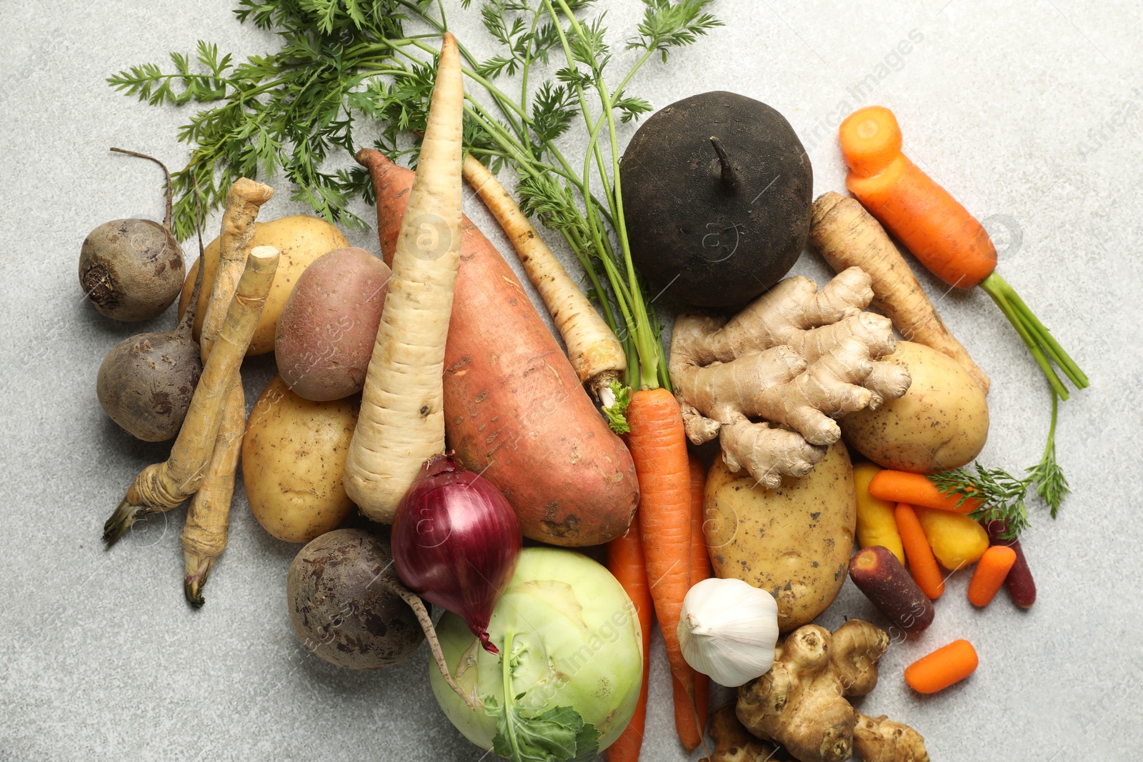 Photo of Different root vegetables on light grey table, flat lay