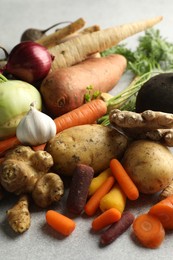 Photo of Different root vegetables on light grey table, closeup