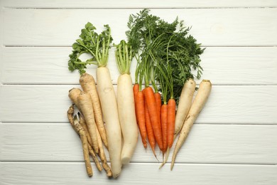 Photo of Different root vegetables on white wooden table, flat lay