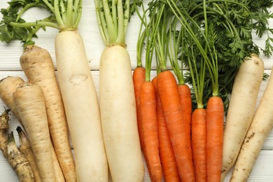 Photo of Different root vegetables on white wooden table, flat lay