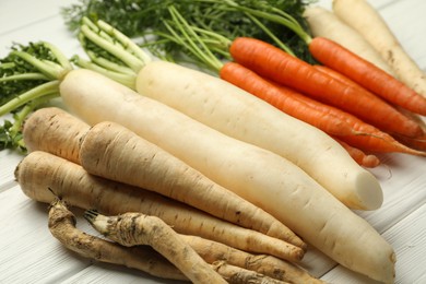 Photo of Different root vegetables on white wooden table, closeup