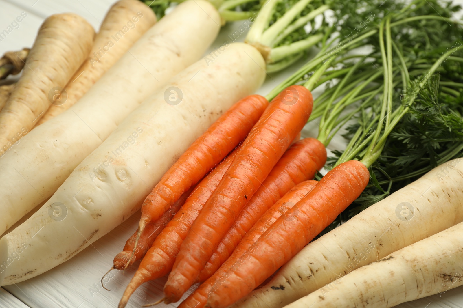 Photo of Different root vegetables on white wooden table, closeup