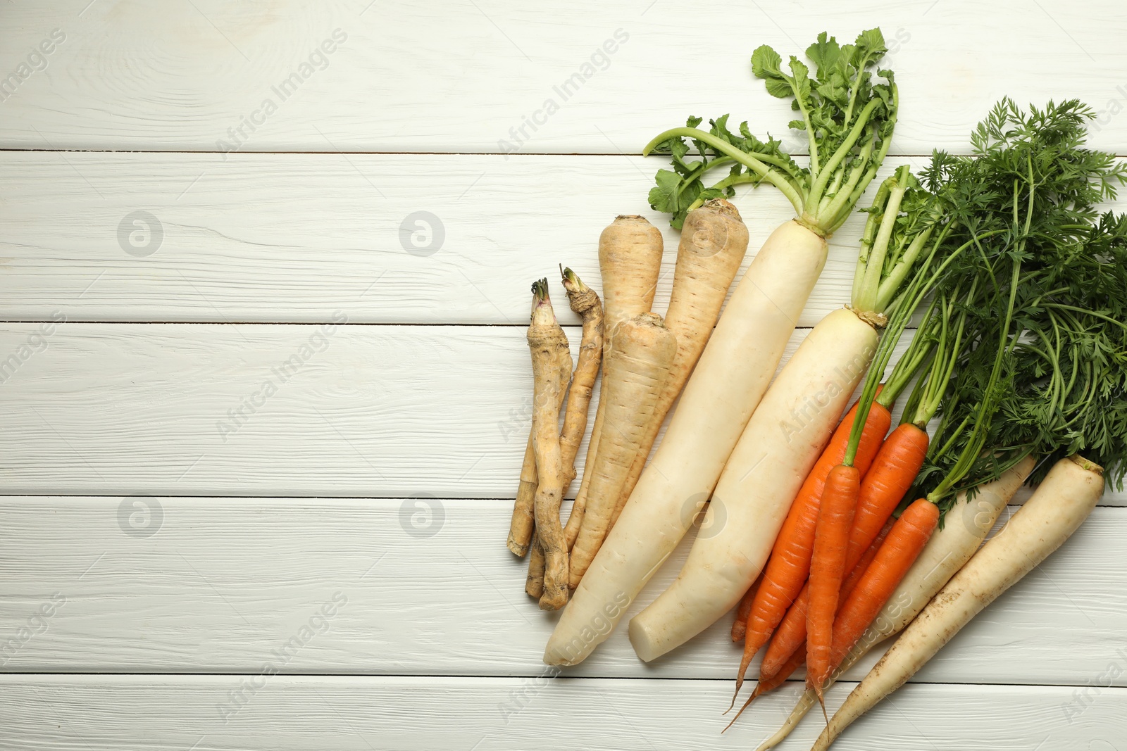 Photo of Different root vegetables on white wooden table, flat lay. Space for text