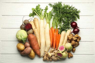 Photo of Different root vegetables on white wooden table, flat lay