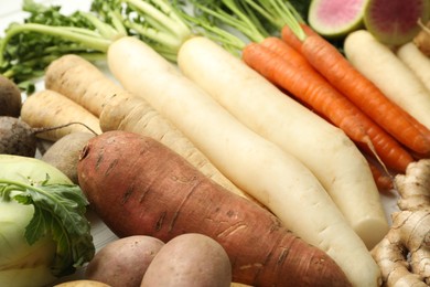 Photo of Different root vegetables on white wooden table, closeup