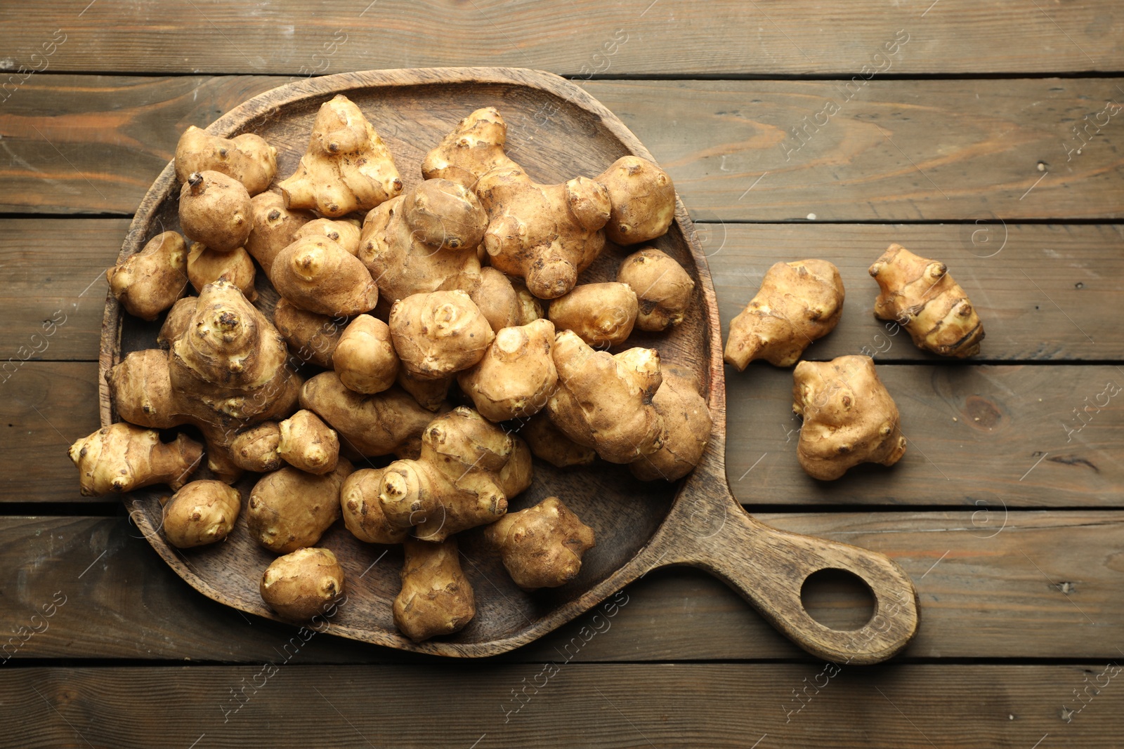 Photo of Raw Jerusalem artichokes on wooden table, top view