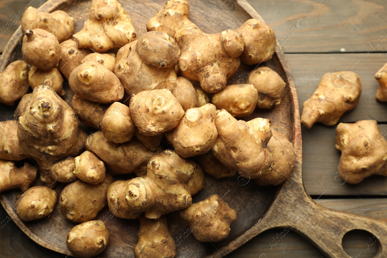 Photo of Raw Jerusalem artichokes on wooden table, top view