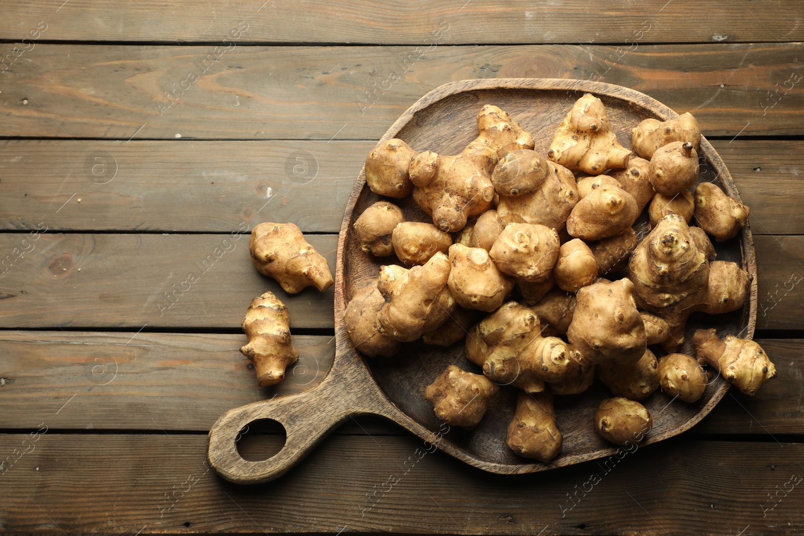 Photo of Raw Jerusalem artichokes on wooden table, top view. Space for text