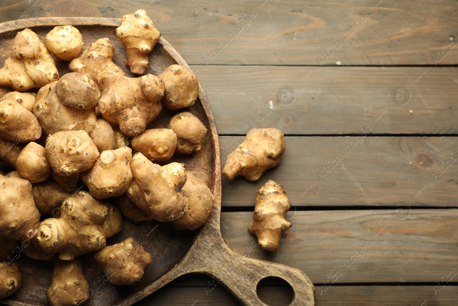 Photo of Raw Jerusalem artichokes on wooden table, top view. Space for text