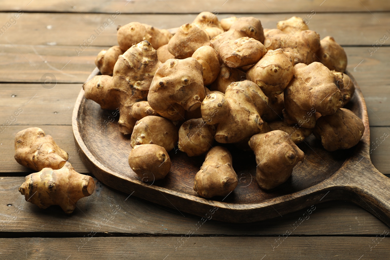 Photo of Raw Jerusalem artichokes on wooden table, closeup