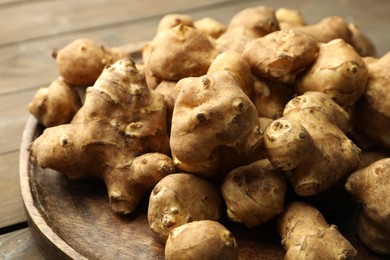 Photo of Raw Jerusalem artichokes on wooden table, closeup