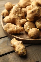 Photo of Raw Jerusalem artichokes on wooden table, closeup