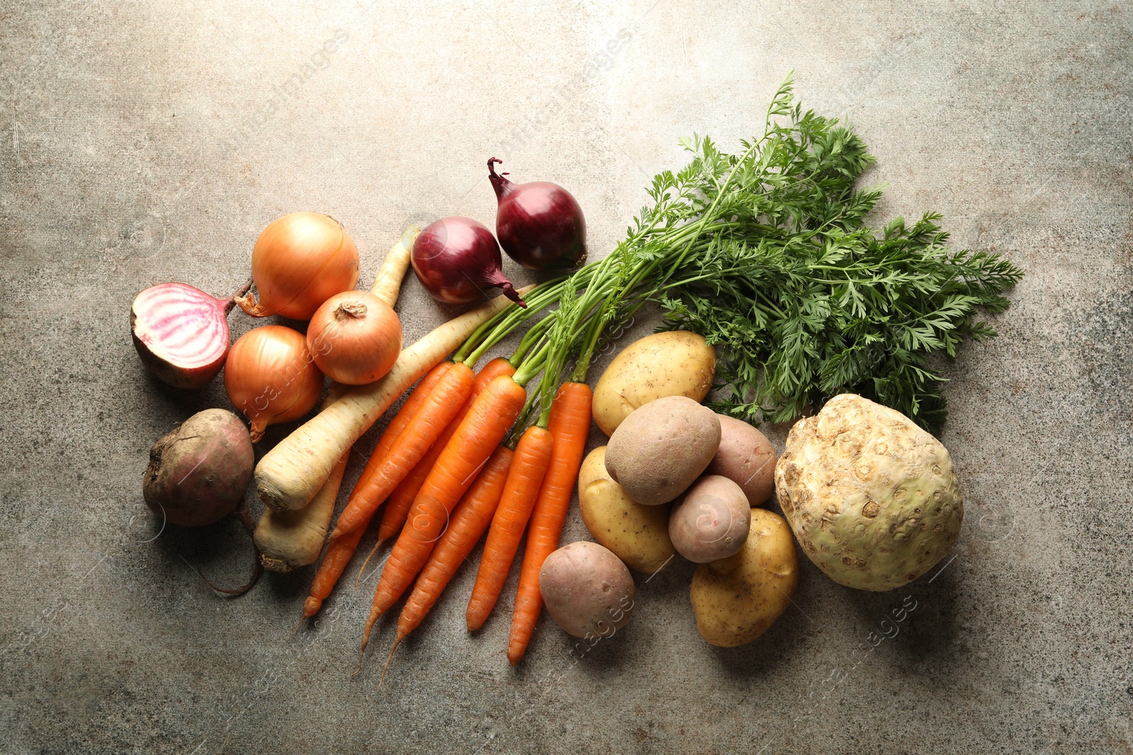 Photo of Different root vegetables on grey table, flat lay