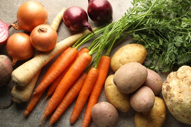 Photo of Different root vegetables on grey table, flat lay