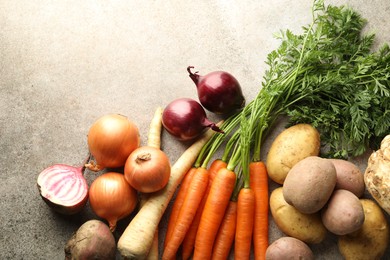 Photo of Different root vegetables on grey table, flat lay. Space for text