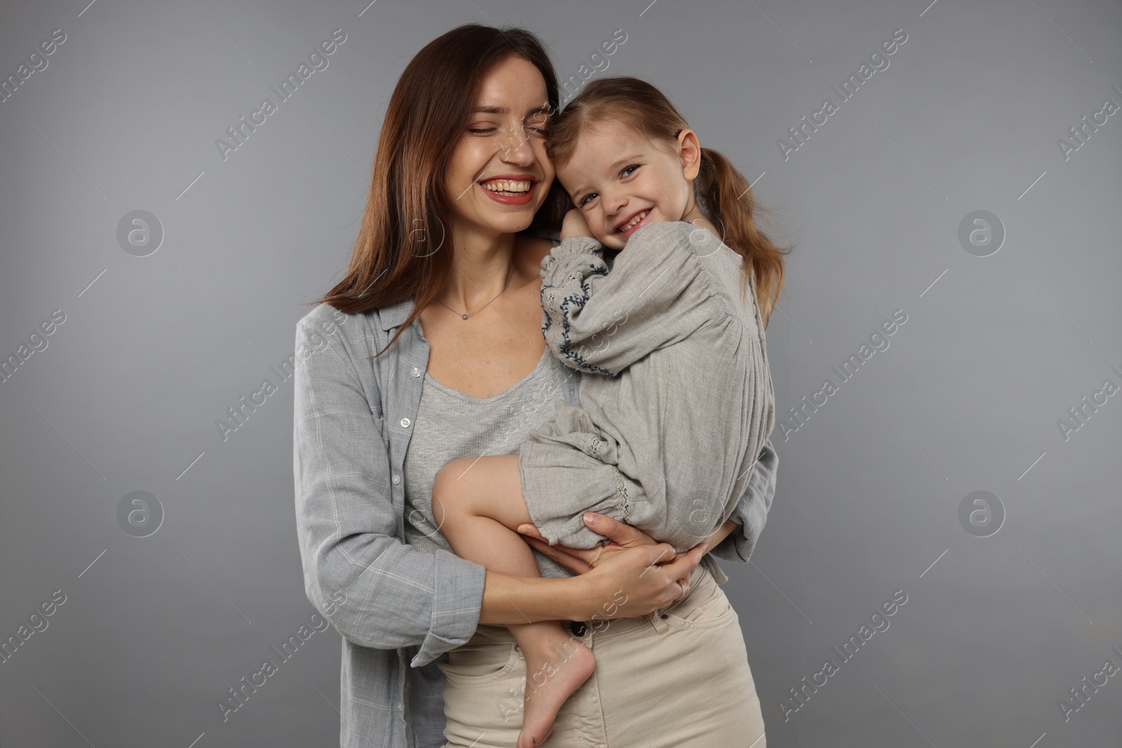 Photo of Happy mother with her cute little daughter on grey background