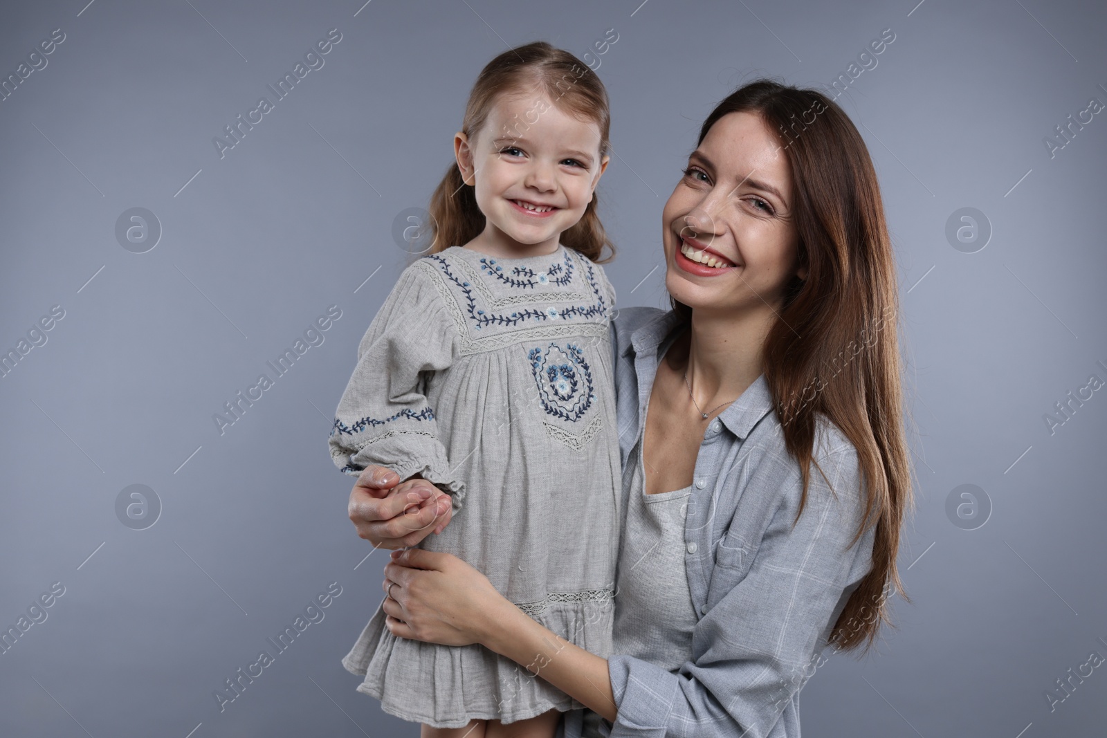 Photo of Portrait of happy mother with her cute little daughter on grey background