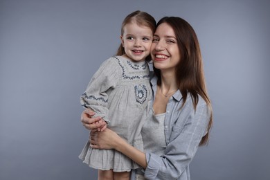 Photo of Portrait of happy mother with her cute little daughter on grey background