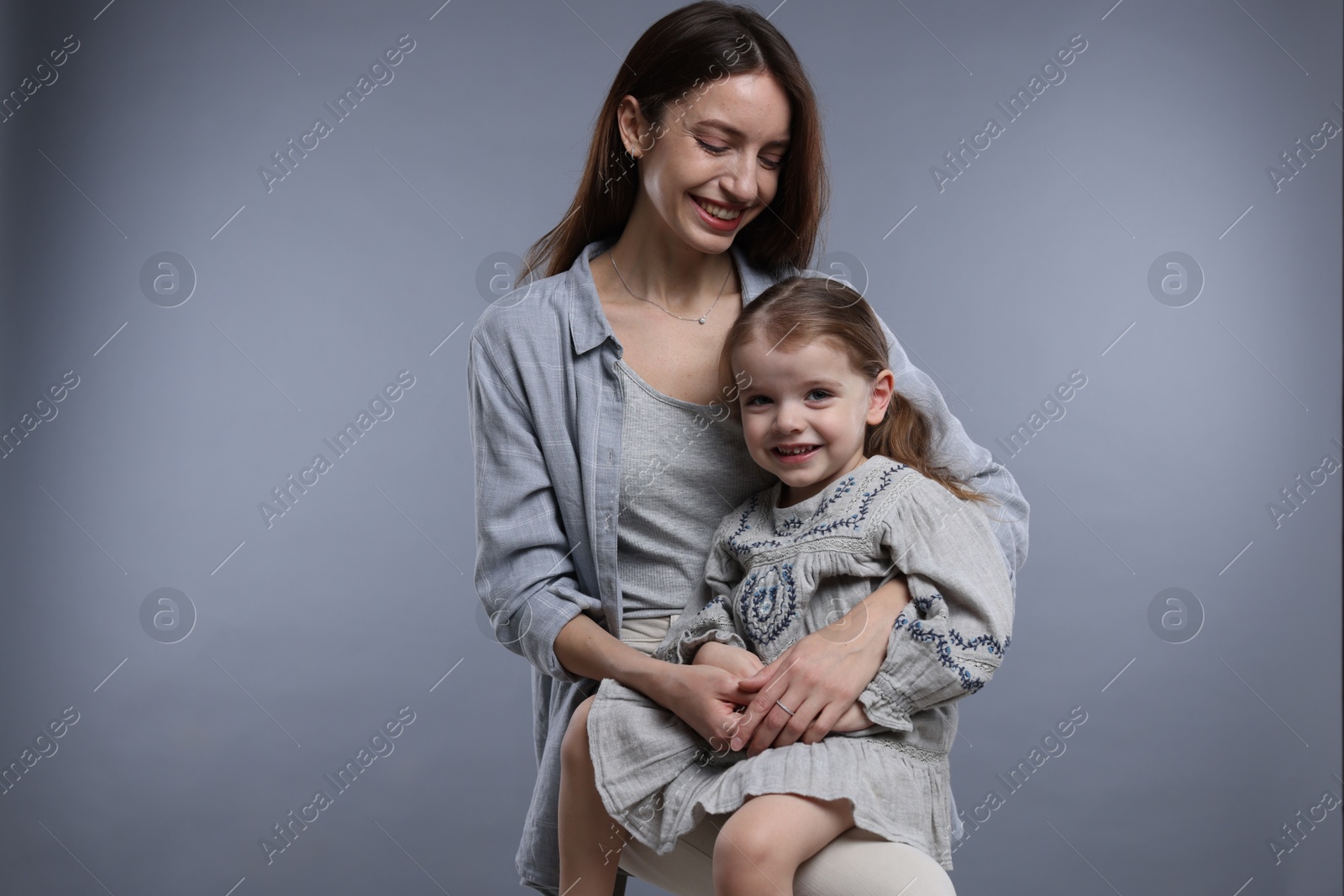 Photo of Happy mother with her cute little daughter on grey background