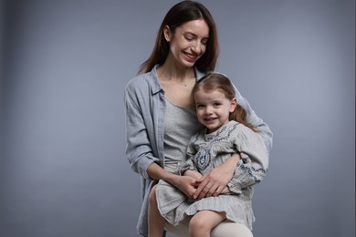 Photo of Happy mother with her cute little daughter on grey background