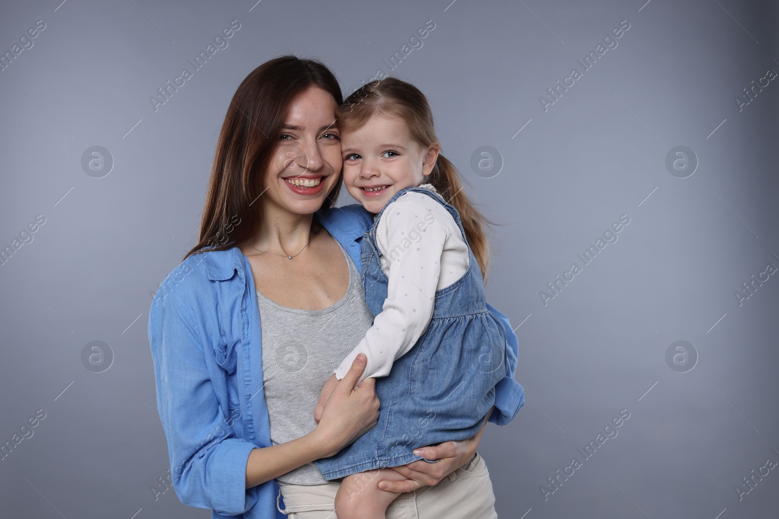 Photo of Portrait of happy mother with her cute little daughter on grey background