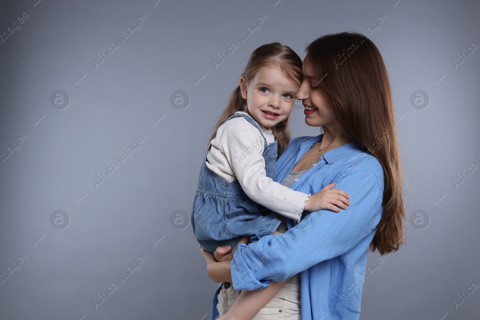 Photo of Happy mother with her cute little daughter on grey background, space for text