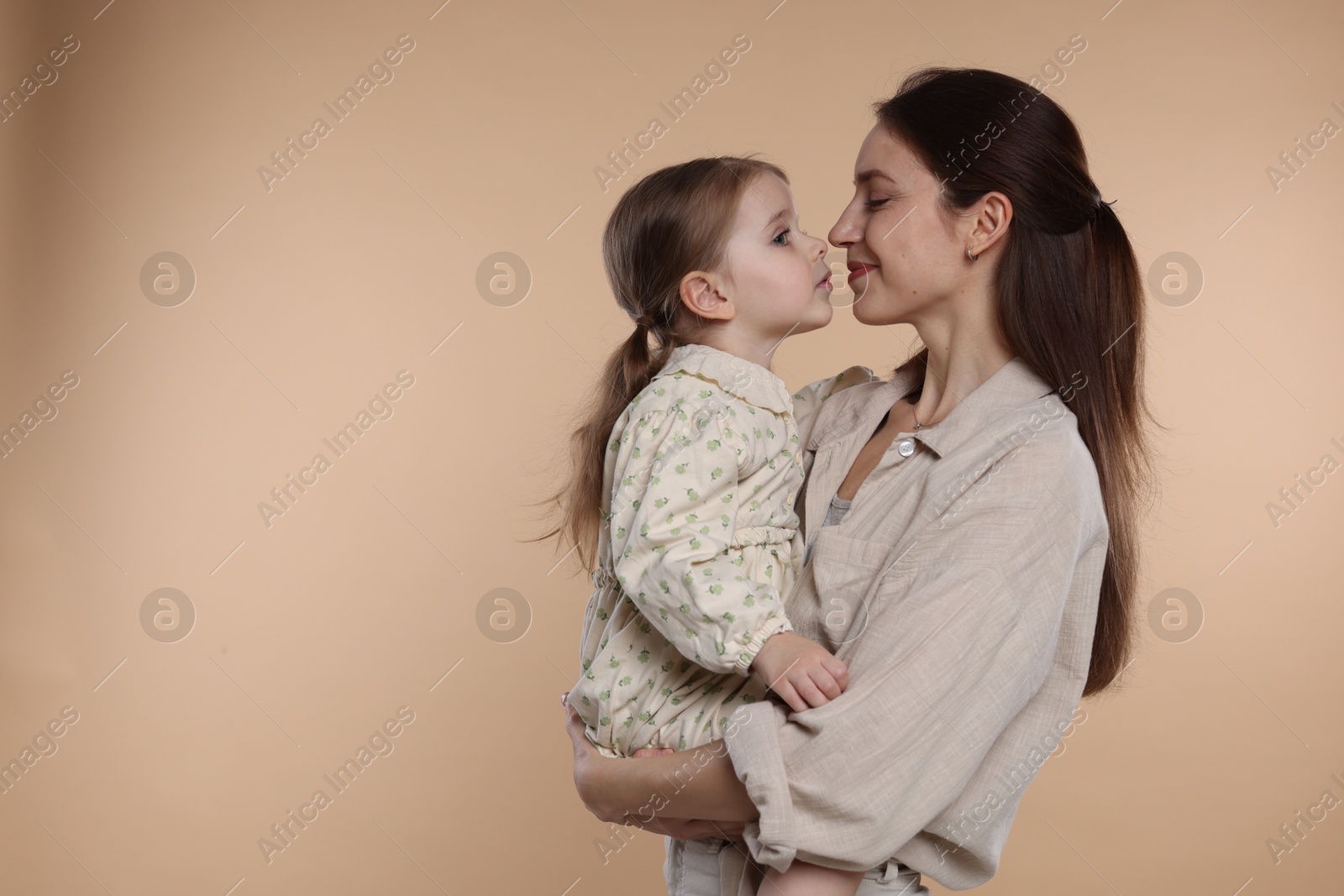 Photo of Happy mother with her cute little daughter on beige background, space for text