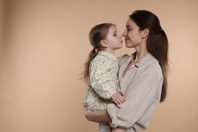 Photo of Happy mother with her cute little daughter on beige background, space for text