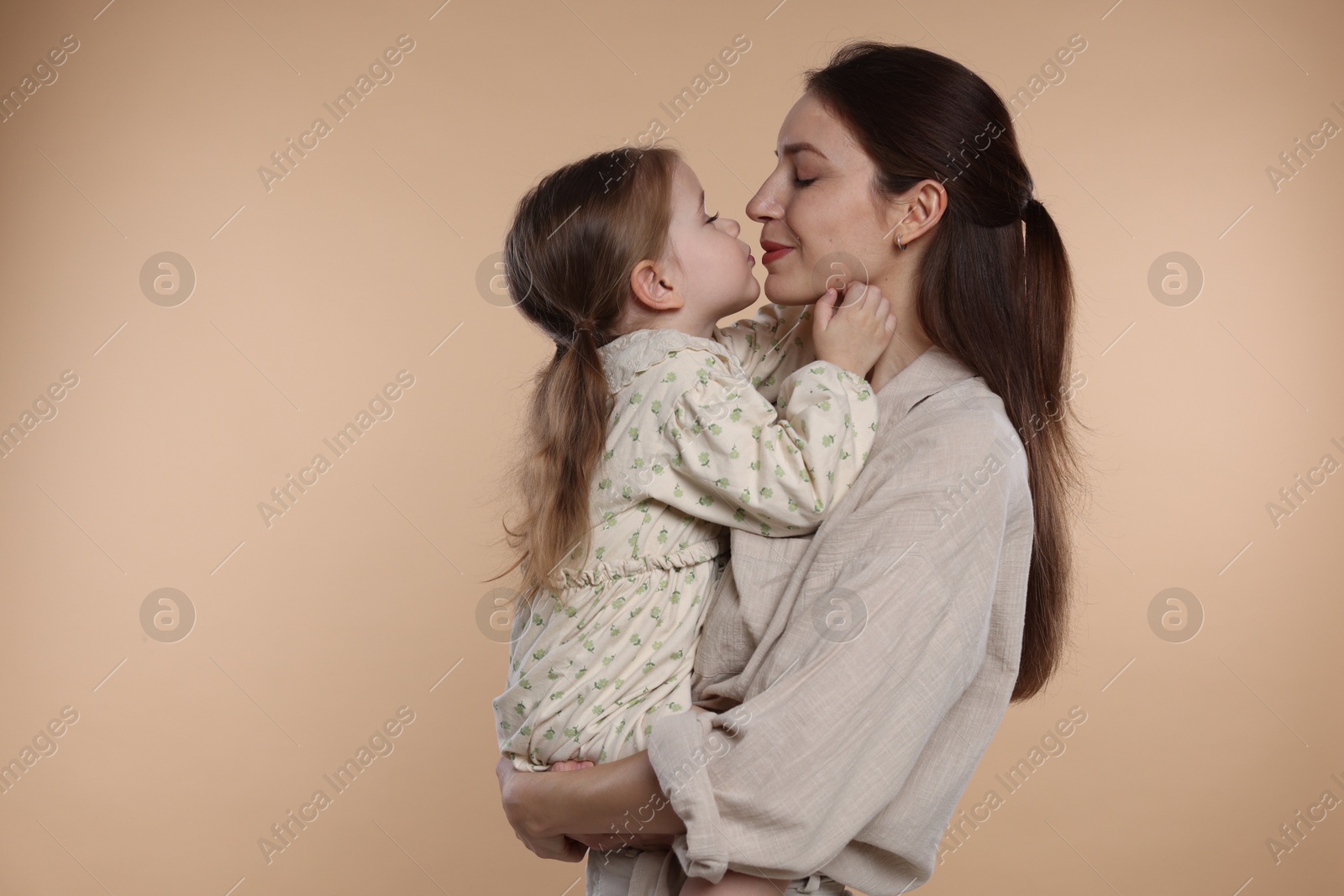 Photo of Beautiful mother with her cute little daughter on beige background